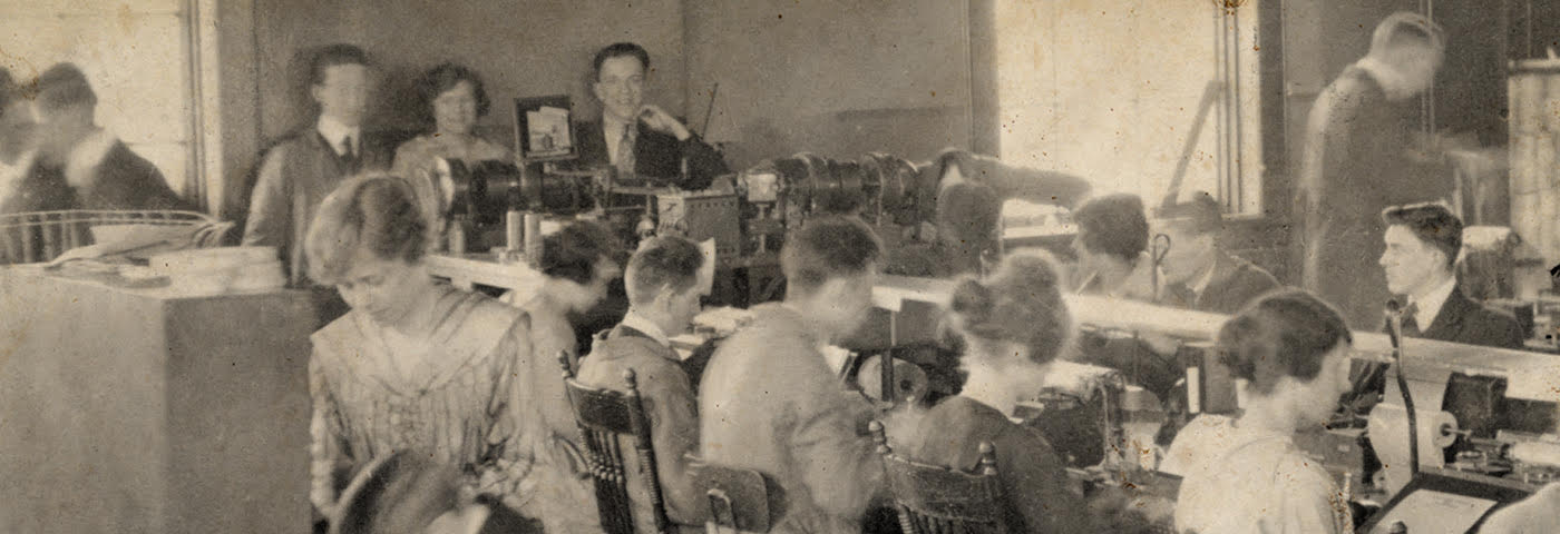 Image en couleurs sépia de personnes travaillant dans un bureau de télégraphie occupé au début du vingtième siècle.