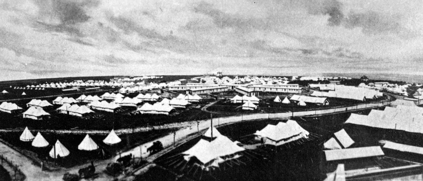 Image is a black and white aerial photograph of a military hospital in France. There are a large number of white tents and other buildings, with several service roads.