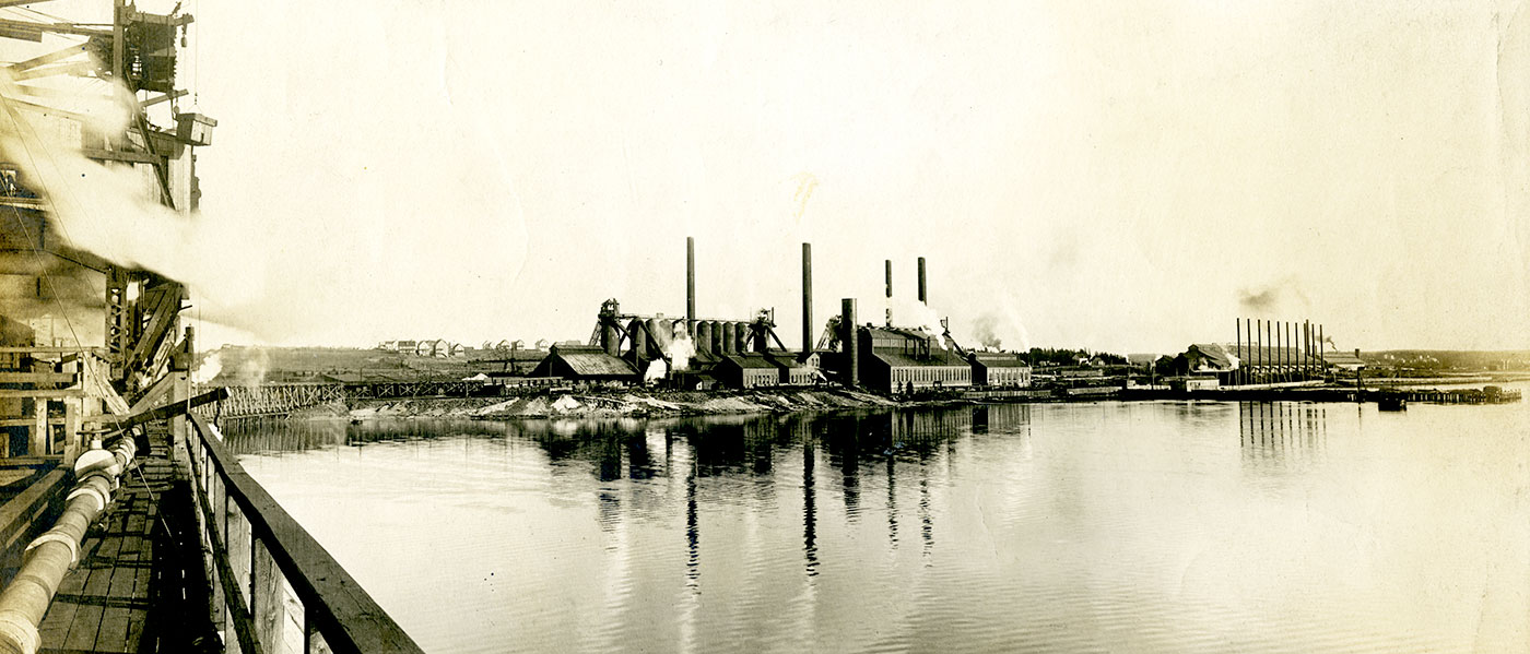Photographie sépia d’une grande usine d’acier prise depuis les quais d’expédition de l’entreprise charbonnière le long du havre de Sydney.