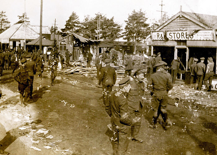 Photographie sépia de soldats en train d’inspecter les dommages dans les rues d’une ville après une émeute après la Première Guerre mondiale.
